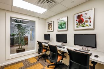 three computer desks in a room with three monitors